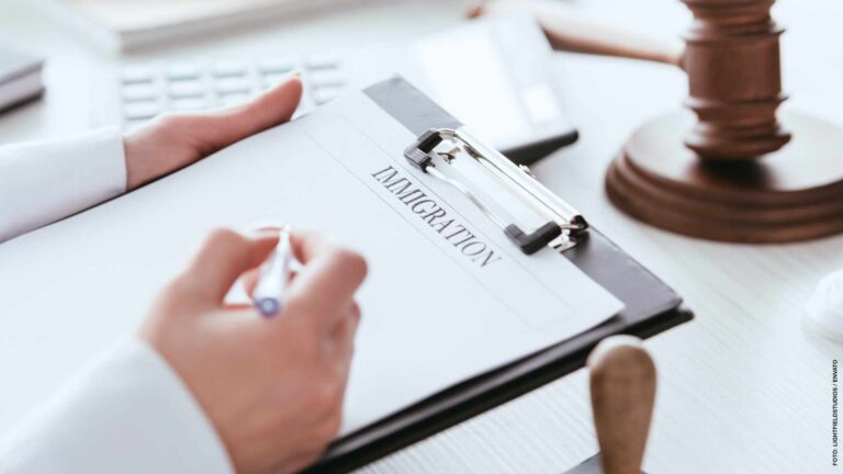cropped view of woman holding pen near document with immigration