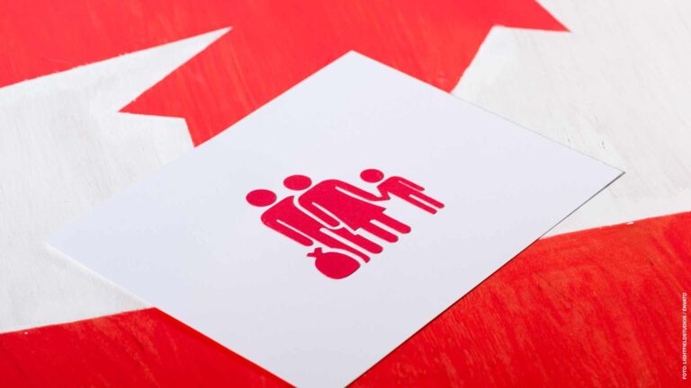 selective focus of white card with family icon on canadian flag,