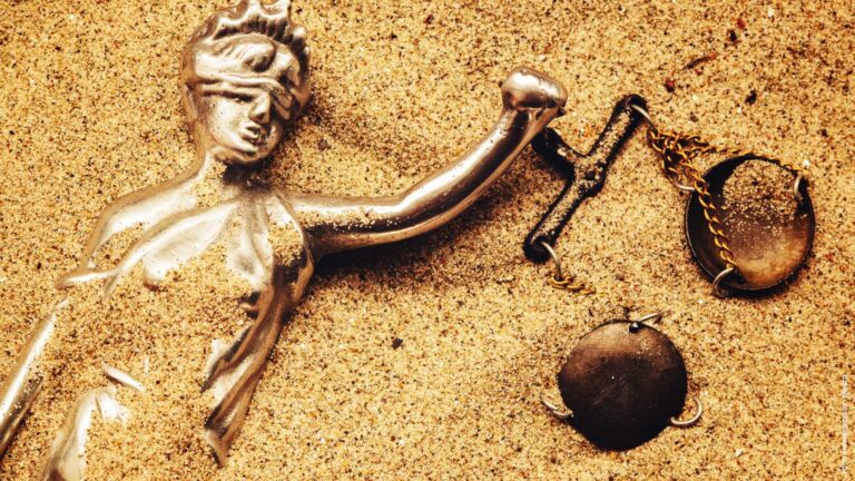 Statue of lady Justice buried in sand