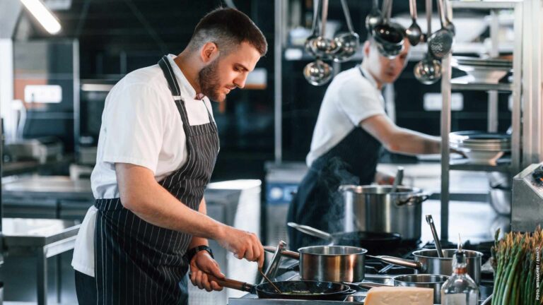 In uniform. Kitchen workers is together preparing the food