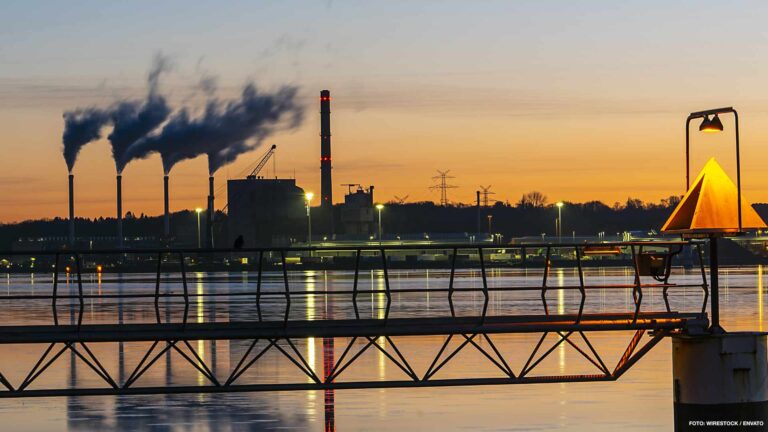 Industrial factory with smoke at sunset - concept of air pollution