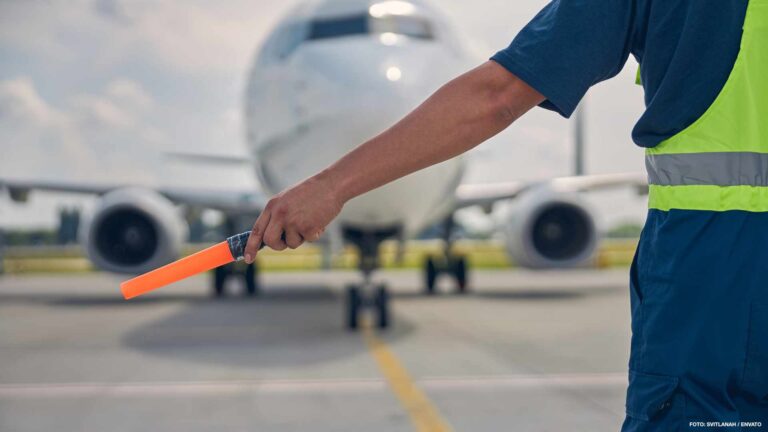 Skilled aircraft marshaller signaling the cockpit crew