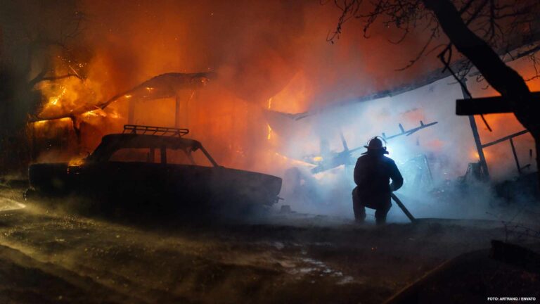 Firefighter putting out the fire of the house and car
