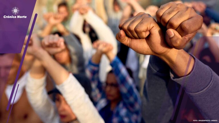 Close-up of crowd of people protesting with clenched fists on the street.