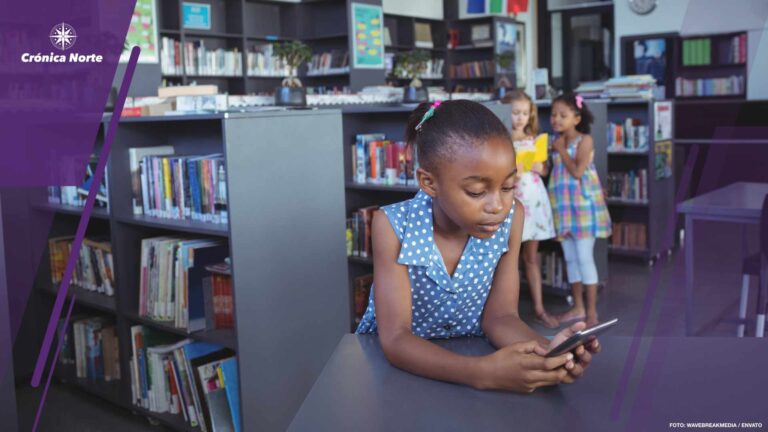 Girl using cellphone at desk in library