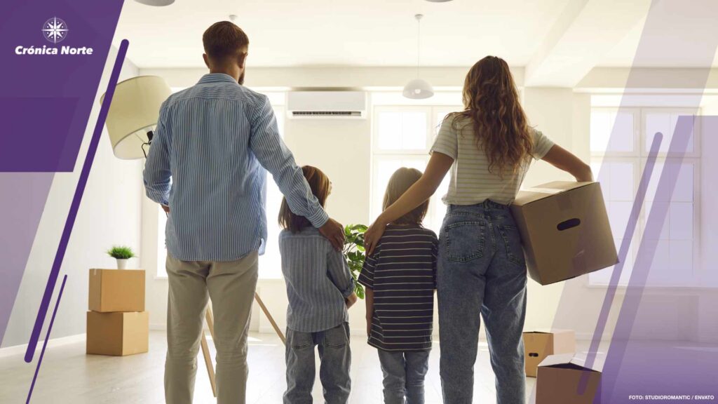 Happy couple with children standing together in their own new house with cardboard boxes.