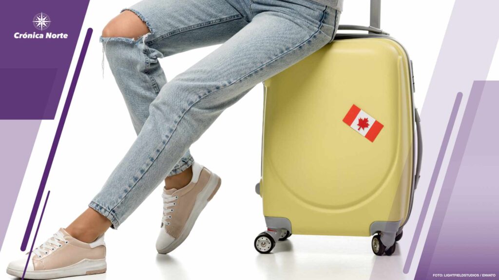cropped view of woman sitting on suitcase with canadian flag sti