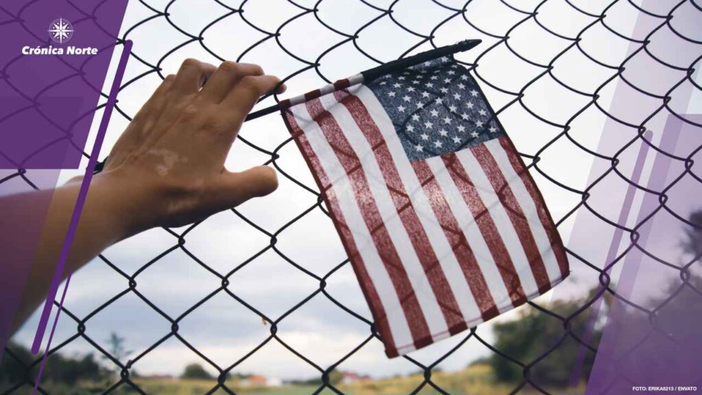Hand holding america flag in front of a barbed fence. Illegal im