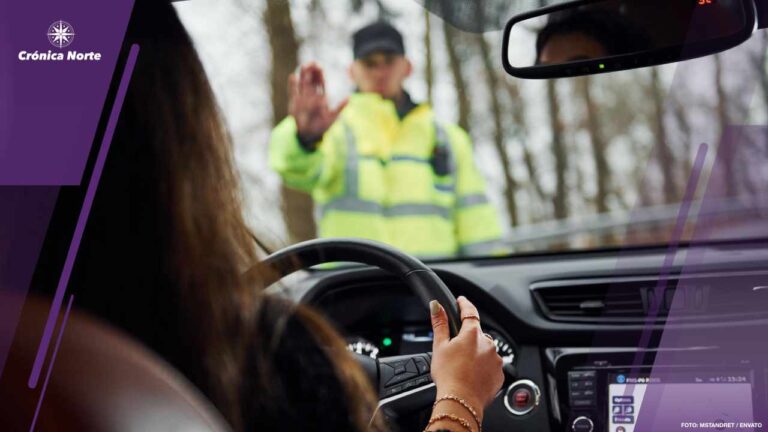 Male police officer in green uniform stops vehicle with female driver on the road